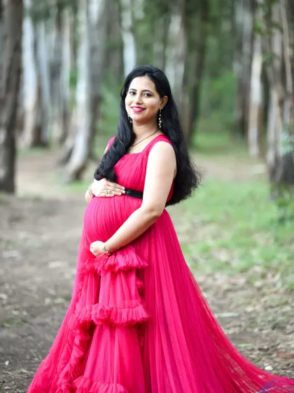 A beautiful portrait of a mom-to-be in a pink gown, posing in a forest setting.