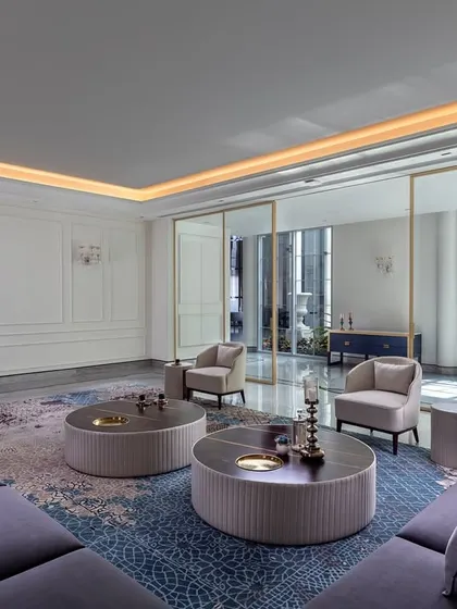 The living area in The Grand Alabaster is a study in calm and quiet luxury. Soft light from the courtyard fills the space, highlighting the plush, modern furniture and the elegant wall mouldings.