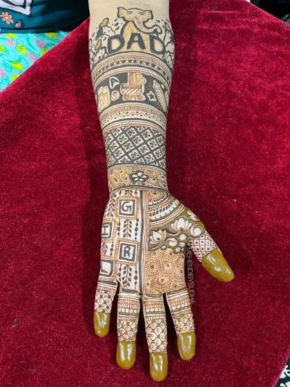 A close-up of the "Dad" arm, featuring an elephant, baby blocks, and the word "GIRL" spelled out, adding a playful guess to the design.
