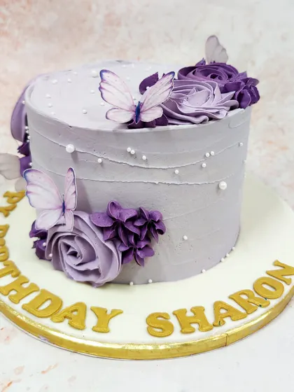 We create a dreamy vision with this lavender butterfly cake. A cascade of purple buttercream roses and delicate, edible butterflies adorns the textured lavender frosting, accented with tiny pearls for a touch of magic and elegance.