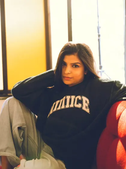 A casual and confident portrait on a red sofa, using the warm indoor light to create a cozy feel.