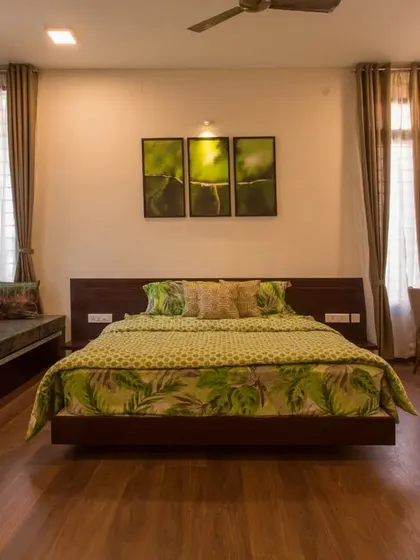 This bedroom is designed with functionality in mind, featuring a bay window with built-in seating, a sleek wooden floor, and a dedicated work-from-home desk.