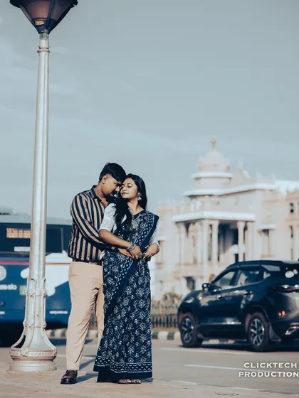 A romantic pre-wedding photo with the Vidhana Soudha in the background, capturing the couple in a classic embrace on a Bangalore street.