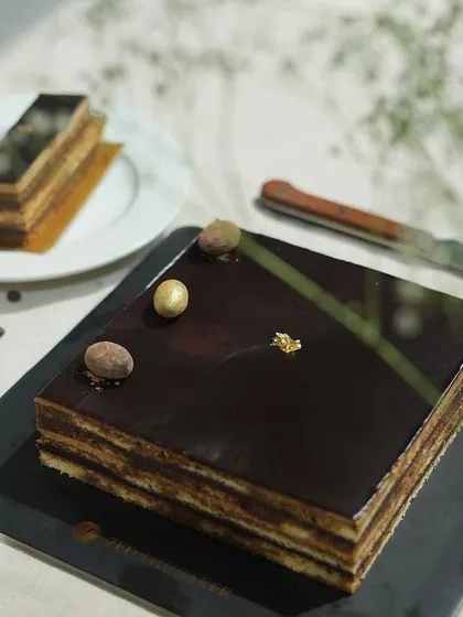 A beautifully lit shot of the Opera Cake, with a sprig of baby's breath adding a soft, natural touch to the sharp, geometric dessert.