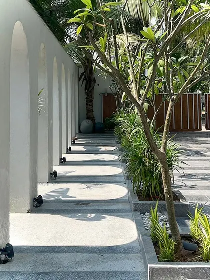 Another perspective on the arched walkway, highlighting the clean lines and the way the structure interacts with the surrounding greenery. The design creates a private garden feel, with the pathway guiding you through an experience of light, shadow, and nature.