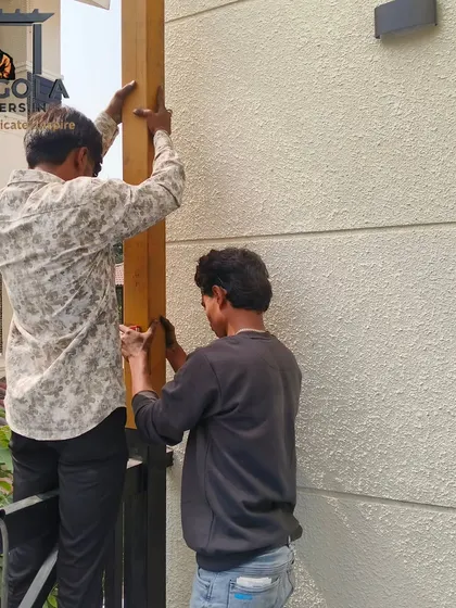 Two team members work together to install a vertical support post for a pergola. This image demonstrates the teamwork and care taken during the on-site assembly to ensure the structure is secure and perfectly aligned.