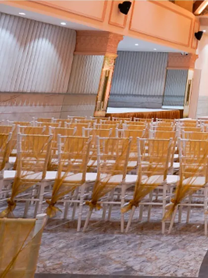 The seating arrangement at Kalidas Marriage Hall, with chairs elegantly draped in gold, awaits the arrival of guests for a grand celebration.