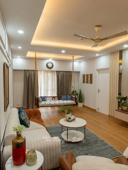 The strategic use of a large mirror panel in this living room creates an illusion of greater depth and space. It reflects the elegant swing and seating area, amplifying the room's light and luxurious feel.