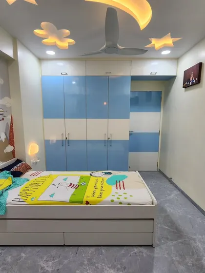 A full view of the kids' room, showing the blue and white wardrobe and the fun ceiling design.
