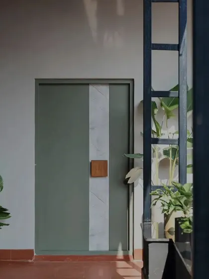 A different perspective of the sage green and marble door, viewed through a structural metal frame. This composition of layers, textures, and indoor plants is a small example of how we approach creating visually interesting spaces.