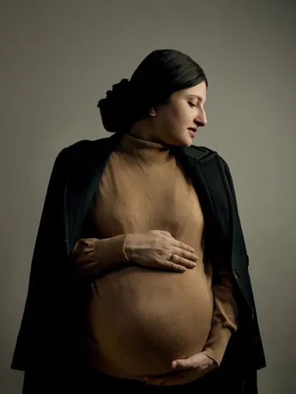 A classic and elegant maternity portrait. The simple, focused lighting highlights the beautiful silhouette of the baby bump, creating a timeless piece of art that you will cherish forever.