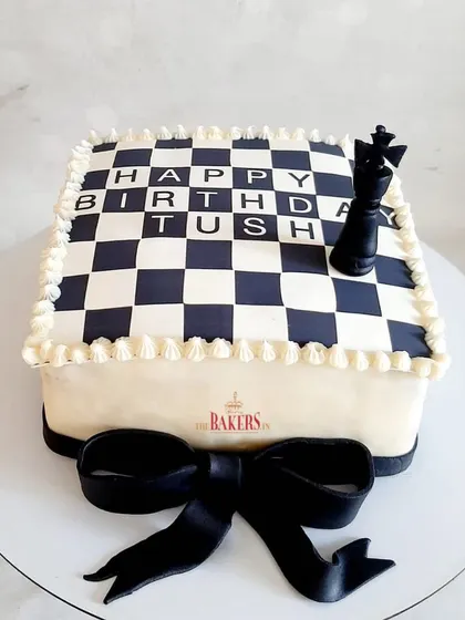 A birthday cake for the King! This chess-themed, no-fondant cake features an edible chessboard top and a king chess piece, finished with an elegant black bow.