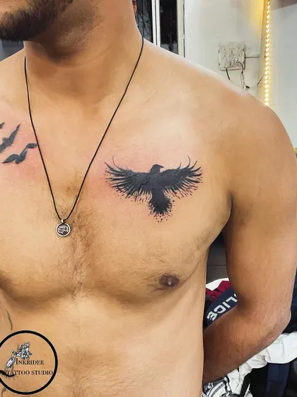 After: The finished piece is a solid black bird with a splatter effect, which completely conceals the old name. This chest tattoo provides a strong and modern look.