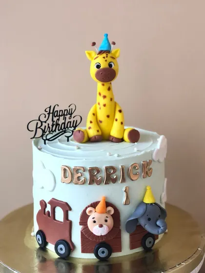 A cute cake featuring a giraffe and an animal train, perfect for a little one's birthday.