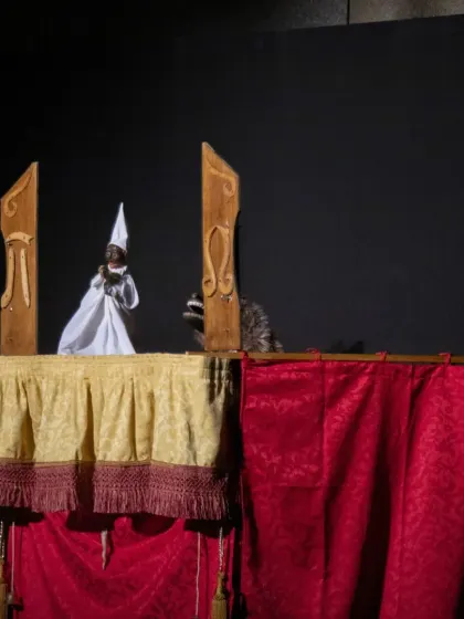 A scene from 'Io, Pulcinella' featuring the main character and a mysterious animal puppet, adding to the comedic and surreal nature of the show.