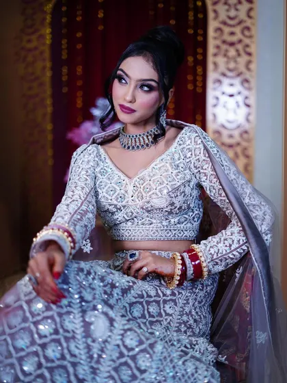 A seated portrait in the pastel lavender lehenga, showing the traditional red chooda for a beautiful contrast.