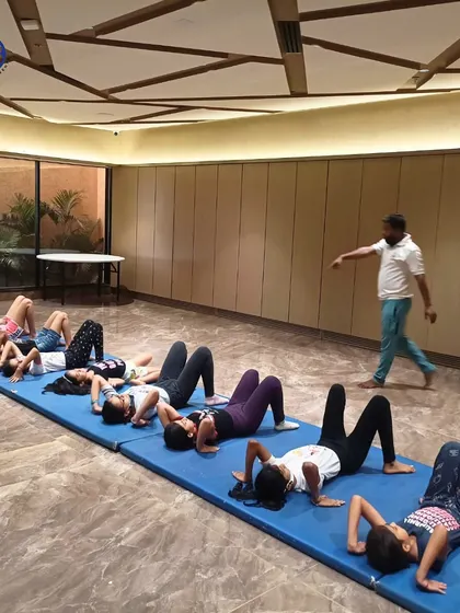 A group of girls works on core strength during an indoor fitness session. We incorporate foundational exercises like crunches into our programs for all age groups.