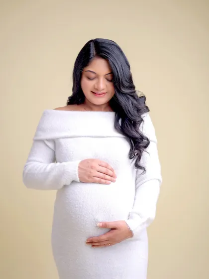 A serene and simple portrait in a comfortable white knit dress. This minimalist approach focuses on the quiet joy and beauty of pregnancy.