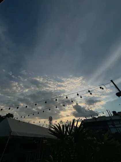 The beautiful evening sky over our rooftop venue, with string lights silhouetted against the clouds, promising a magical night ahead.