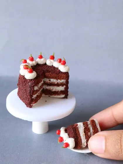 Another angle of the layered red velvet cake, held in hand to show its tiny scale.