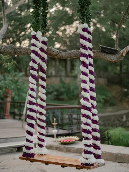 A beautifully decorated swing with purple and white floral ropes, a perfect spot for both rituals and romantic couple photos.