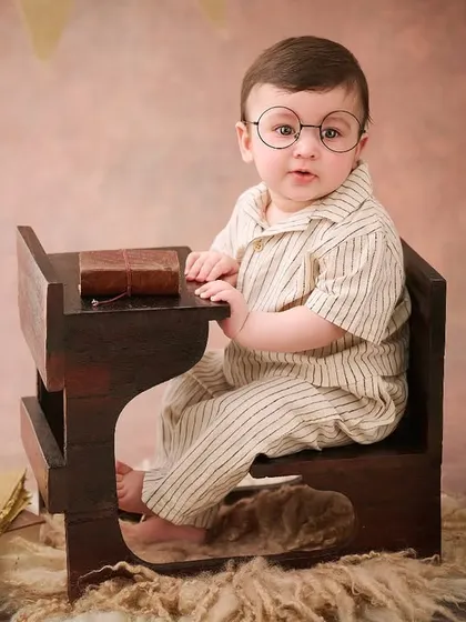 A little scholar hard at his desk. This vintage school theme, complete with tiny glasses and books, is a charming and unique concept for a sitter session.