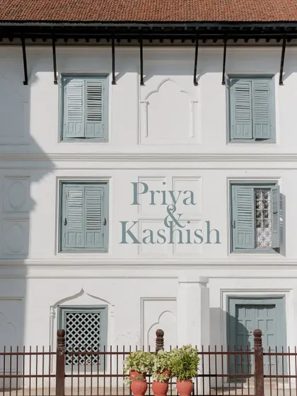 A simple yet elegant graphic announcing the wedding of Priya and Kashish, set against the charming architecture of their Kathmandu venue.