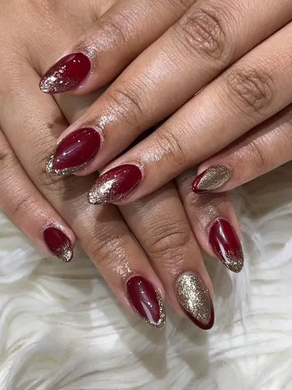 A classic bridal look featuring deep red gel polish on almond-shaped extensions, accented with a brilliant gold glitter ombre. This is a perfect choice for making a statement on your wedding day.