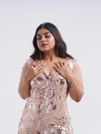 A serene portrait in a rose gold sequin gown, showing the beautiful shimmer and delicate shoulder chain details.