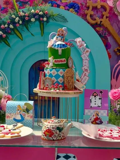 The dessert table at Ahana's 'Onederland' party, centered around an amazing themed cake. The setup includes custom cookies and props that bring the Mad Hatter's tea party to life.
