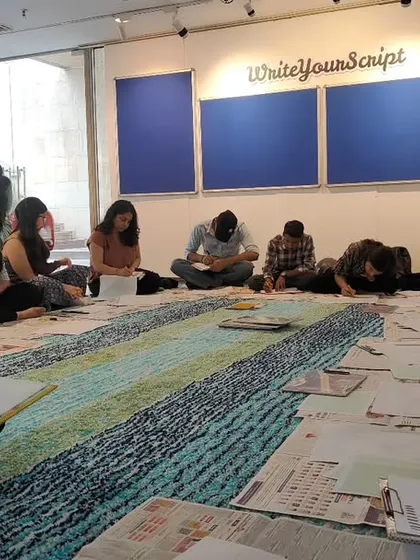A wide shot of participants deeply engaged in the calligraphy workshop, seated on the floor of our gallery. The atmosphere is one of focused creativity and shared learning.