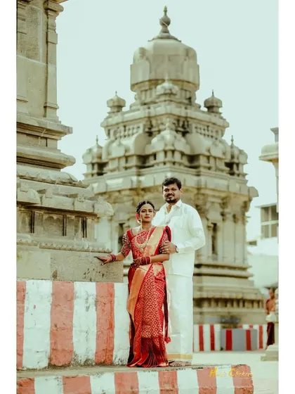 A timeless portrait of a couple in traditional wedding attire, standing before a historic temple.