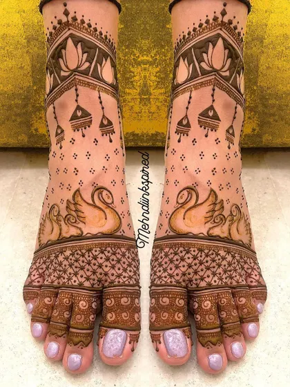 Your bridal look is complete with beautiful feet mehndi. This elegant design features graceful swans and delicate jhumka motifs, ensuring you look perfect from head to toe.