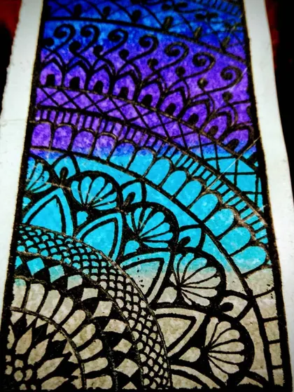A closer look at the details of the mandala bookmark. The fine black ink lines define the patterns against the blended color background.