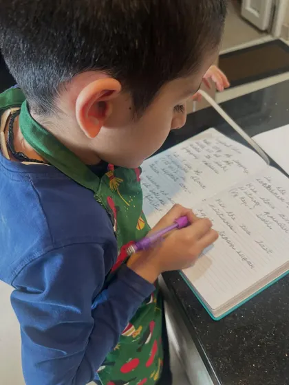 This was a beautiful moment from a gingerbread cookie baking session. The student is carefully writing down the recipe, practicing literacy and sequencing skills while engaging in a fun, real-world activity. Learning is integrated into every step.