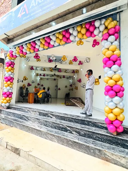 An inauguration decoration for a new office. The entrance is decorated with a vibrant balloon arch in pink, yellow, and white.