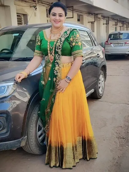 A full-length view of a client looking beautiful in our yellow and green half saree, available for rent.