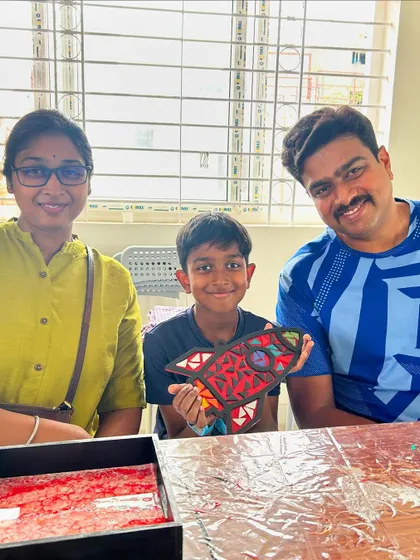 A family proudly displaying their son's mosaic rocket ship art.