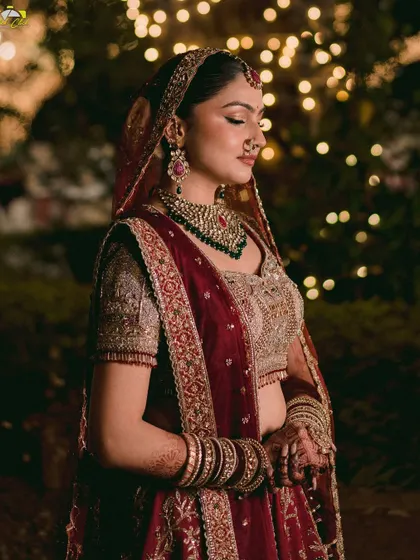 A close-up portrait of the bride, her face softly lit and her eyes closed in a moment of serenity. The rich colors of her outfit and the warm background lights create a stunning image.