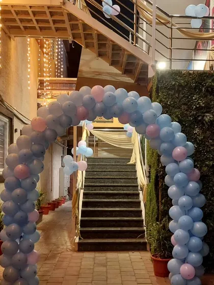 We use balloon arches to create beautiful transitions within a venue. This pastel blue and pink arch frames a staircase, leading guests to the main event area and adding a touch of celebration to the journey.