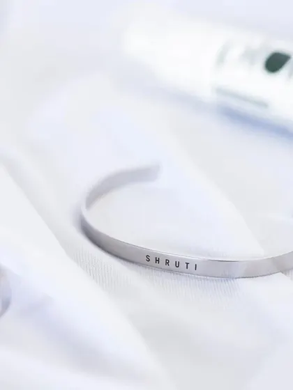 A silver cuff engraved with 'SHRUTI', presented in a bright, clean setting to emphasize its sleek and modern design.
