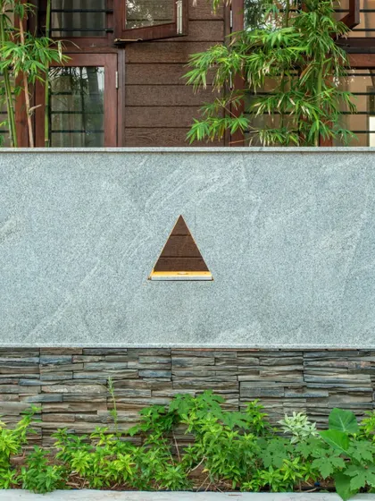 A detail of the compound wall, showing the combination of stacked slate stone, granite, and a triangular cutout that adds a unique design signature to the project.
