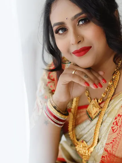 A beautiful close-up portrait, highlighting the flawless skin, red lip, and intricate gold jewellery.