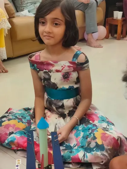 A birthday girl sits proudly with her completed rocket, ready for the main event. Each child gets to keep their creation as a party favor.