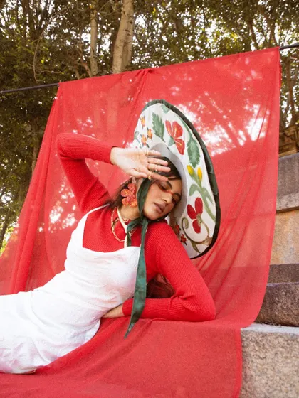 A reclining pose that highlights the floral pattern on the hat.