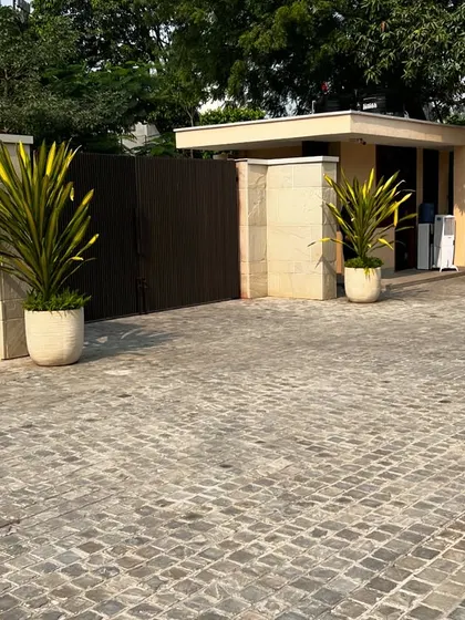 The cobblestone driveway and simple planters at the main gate of the Sultanpur farmhouse.