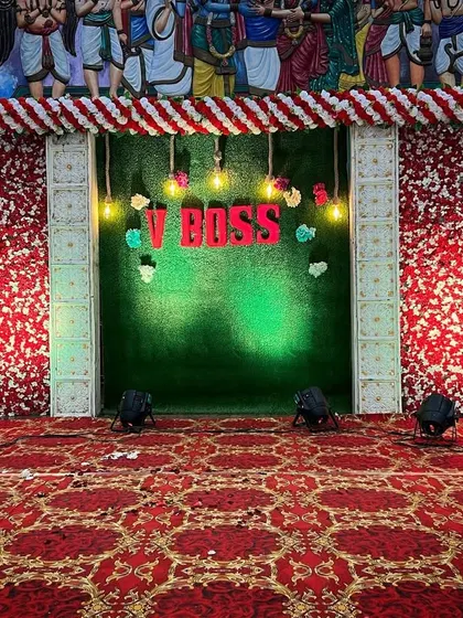 An affordable and vibrant stage decor option using high-quality artificial flowers. This setup is perfect for receptions and includes a custom name sign and spotlights for a dramatic effect.