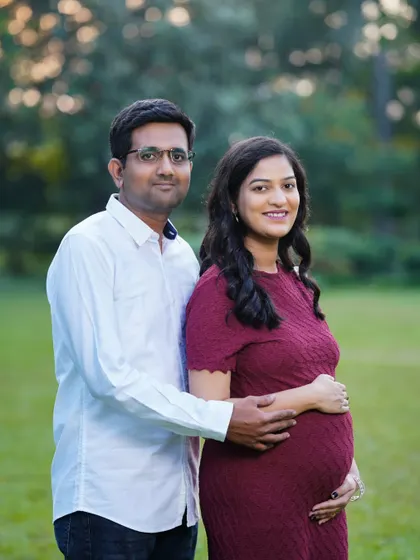 A classic and happy portrait of an expecting couple in a park setting. Their comfortable pose and the natural background make for a timeless memory.