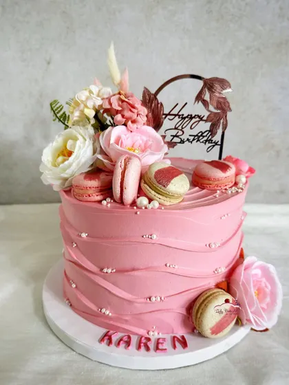 A rose gold beauty. This pink cake is decorated with macarons, flowers, and a textured buttercream finish for a chic and modern look.