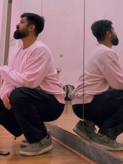 A different angle of the squat pose against the mirror, showing reflection and form.